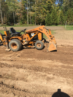 Back dragging bucket to scrap up rocks and clay.